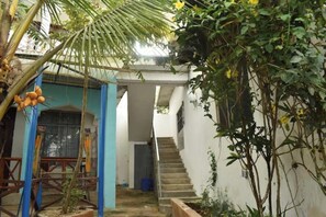 A narrow outdoor corridor with a staircase leading to a higher level, surrounded by vegetation and a palm tree. - King Bed with Garden Views Kendwa. (Kendwa)