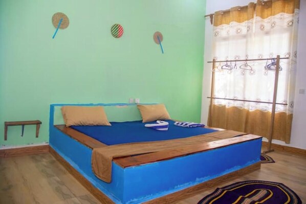 Een kamer met een bed, een kleintje tafel en een raam met gordijnen.