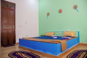 Een kamer met een bed, een houten deur en een groene wand.