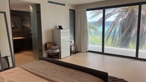 A modern bedroom with a large bed, a desk, and a view of the ocean. - Daniel Bay - Modern 6-bedroom beachfront house in Willoughby Bay (St Paul)