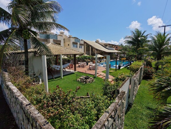 A resort with a swimming pool, outdoor seating, and a well-maintained lawn.
