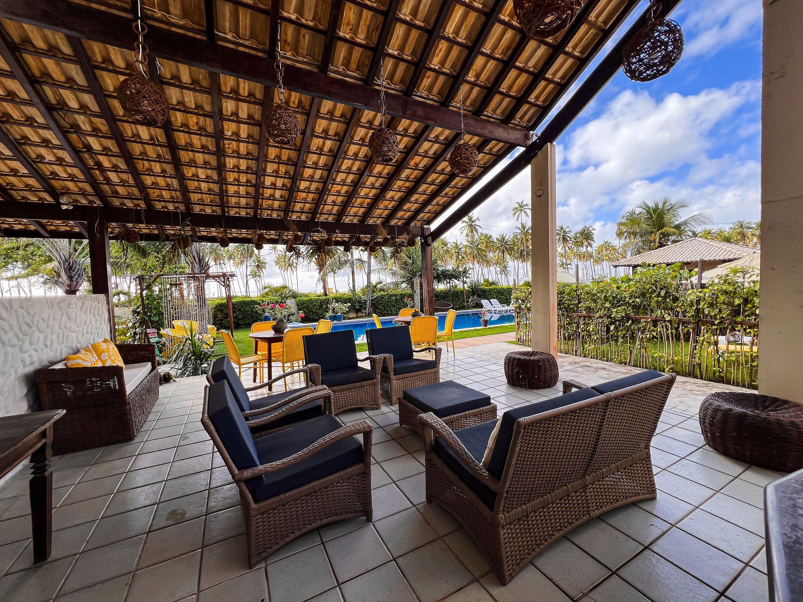 A covered outdoor seating area with wicker furniture and a pool in the background.