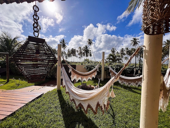 A hammock set up between two poles in a grassy area with a clear sky and palm trees in the background.
