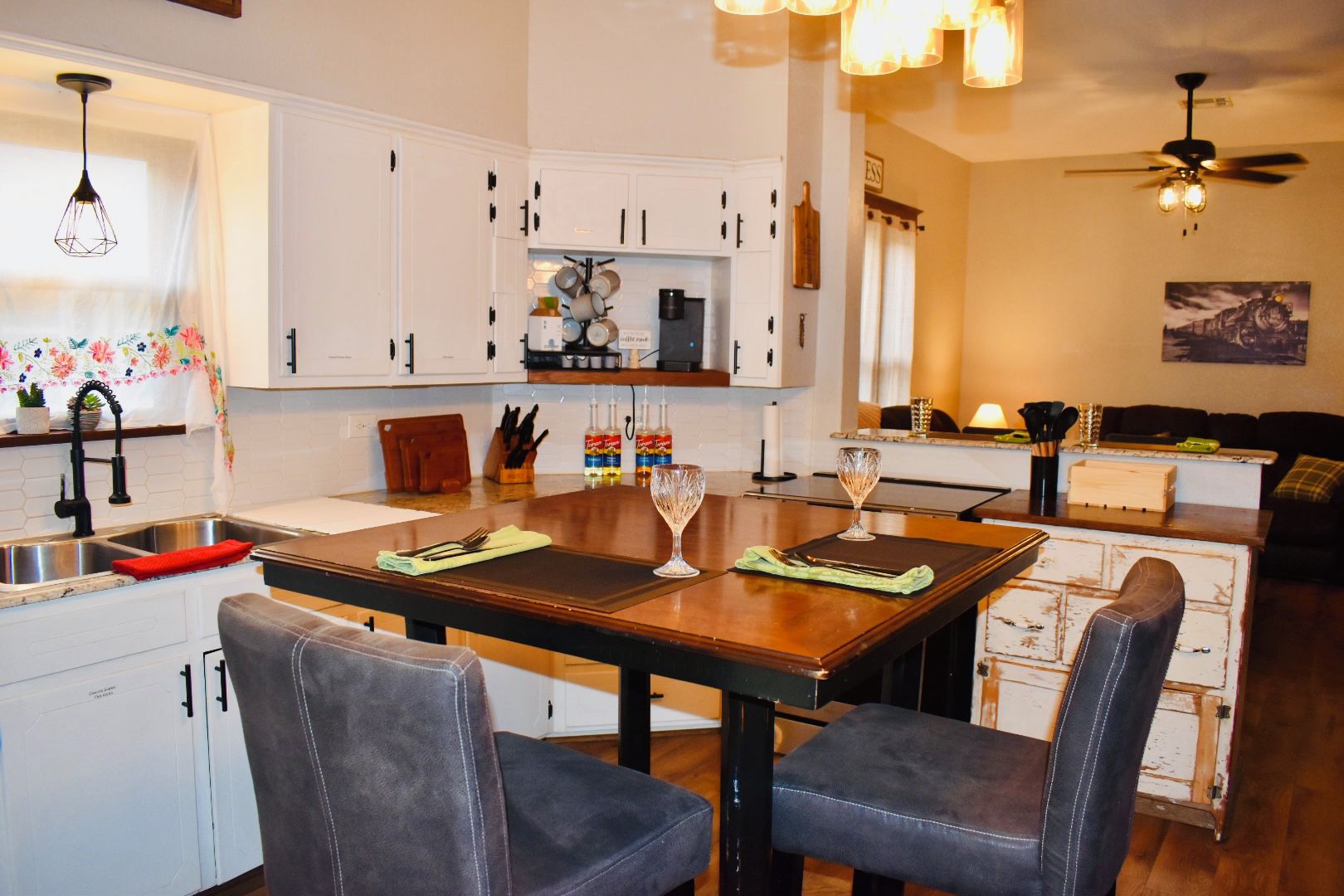 A kitchen with white cabinets, a dining table with chairs, and a ceiling fan.