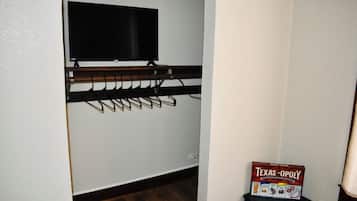 A room with a mounted television, a coat rack, and a Texas-Opoly game box on a table.