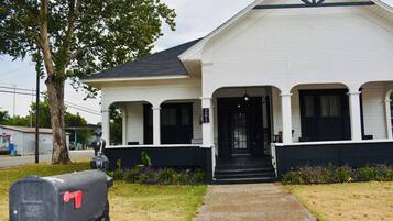 A white building with a black front door, a mailbox, and a tree in the background.