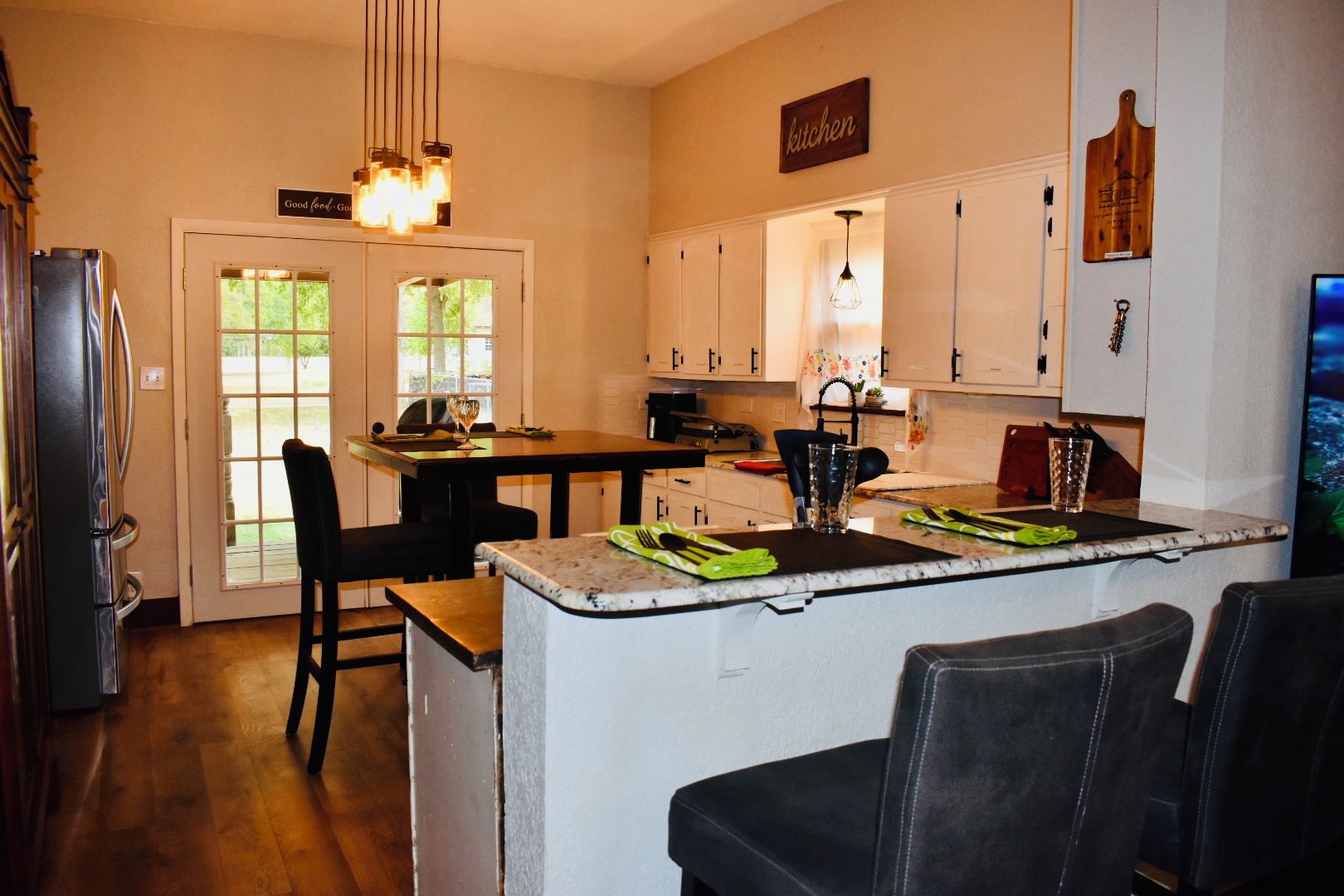 A kitchen with a dining area, a refrigerator, a dining table with chairs, and a kitchen island with a sink.