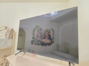 Ein Fernseher auf einem Ständer mit einem dekorativen Gegenstand auf der linken Seite.