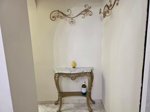 Eine Sitzecke mit einem Marmortisch, einer Wanddekoration und einer Handdesinfektionsflasche.
