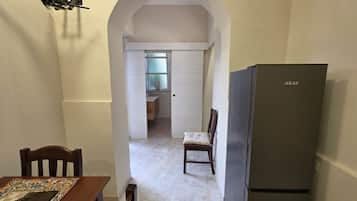 Eine Küche mit einem Kühlschrank, einem Esstisch mit Stühlen und einem Durchgang zu einem Badezimmer.