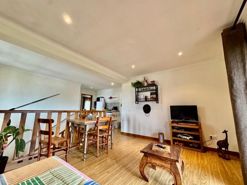 Una sala de estar con una mesa de comedor de madera, sillas, un televisor y una estantería.