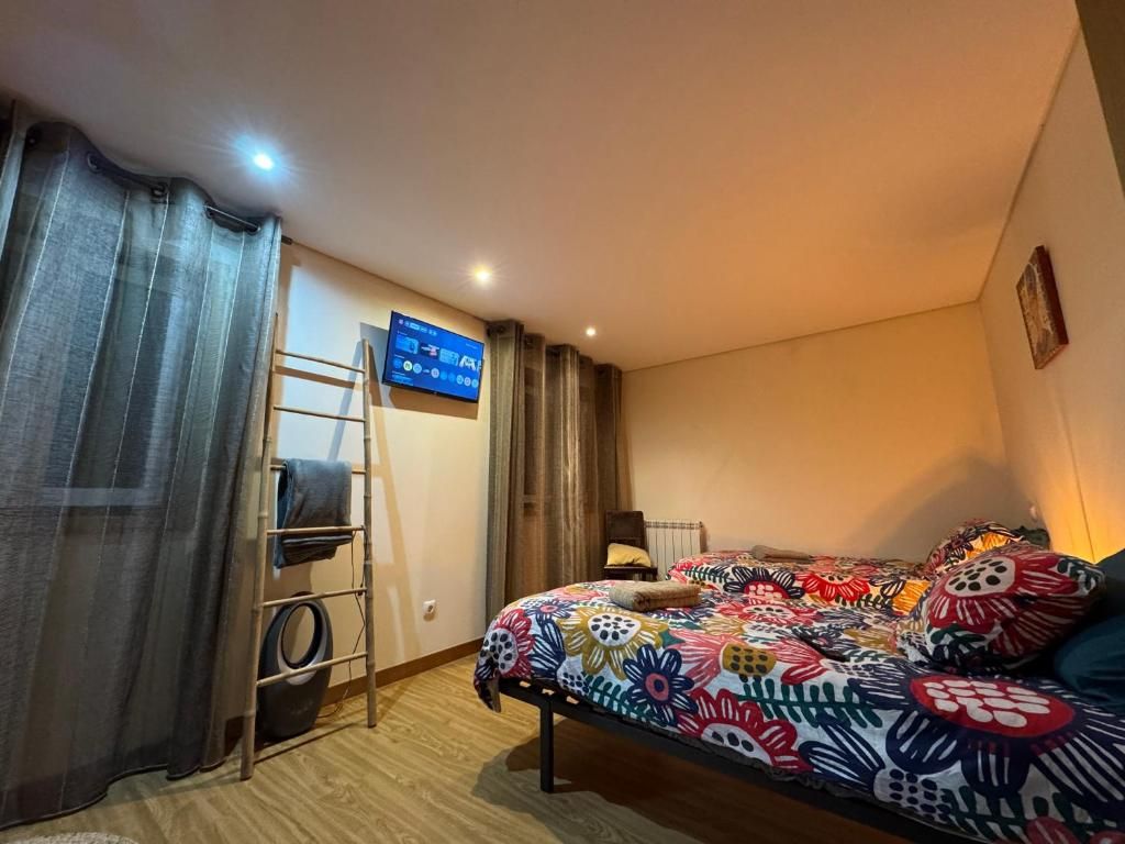 Ein Schlafzimmer mit einem Bett, einer Leiter, einem Fernseher und einem an der Wand befestigten Bildschirm.