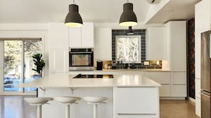 A modern kitchen with a large island, stainless steel appliances, and pendant lighting. - Luxury Cottage - Detox & Relaxation (Stone Mills)