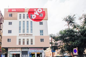 Un edificio de varios pisos con letreros que indican 'Hotel Priya Residency' y 'Maitri Arcade'.