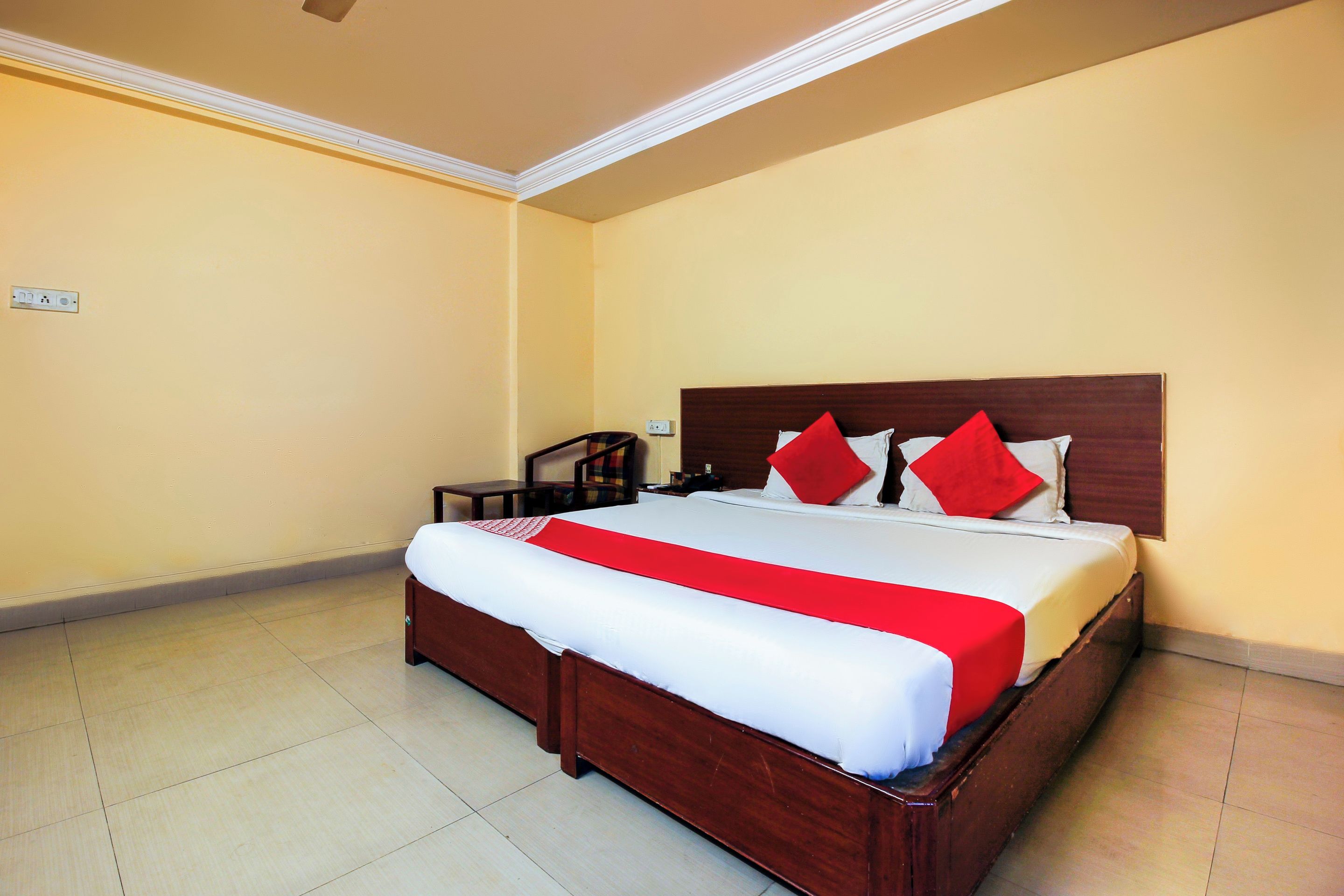 Una habitación de hotel con una cama grande, cabecera de madera y colcha roja y blanca.