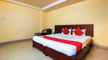 Una habitación de hotel con una cama grande, cabecera de madera y colcha roja y blanca.