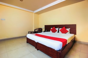 Una habitación de hotel con una cama grande, cabecera de madera y colcha roja y blanca.