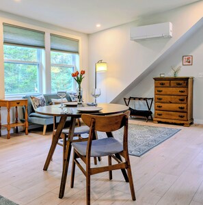 A dining area with a round table, chairs, a vase with flowers, and a lamp. - Cozy Coastal Studio Cottage a short walk to Pemaquid Beach (Bristol)