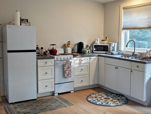 A kitchen with white cabinets, a white refrigerator, a stove, a microwave, and a sink. - Cozy Coastal Studio Cottage a short walk to Pemaquid Beach (Bristol)