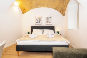 A bedroom with a bed, two wall-mounted artworks, a nightstand, and a chair. - Quiet studio overlooking the garden | Air conditioning | Near Mariahilfer Str. (Wien)
