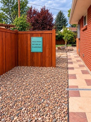 A wooden fence with a sign indicating 'MILE HIGH RETREAT PARKING' and a gravel area. - Upscale Two-Suite Denver Retreat - Sleeps 11 (Denver)