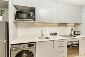 A modern kitchen with a Bosch microwave, sink, and dishwasher. - Newlands Peak Studio Apartment (Cape Town)