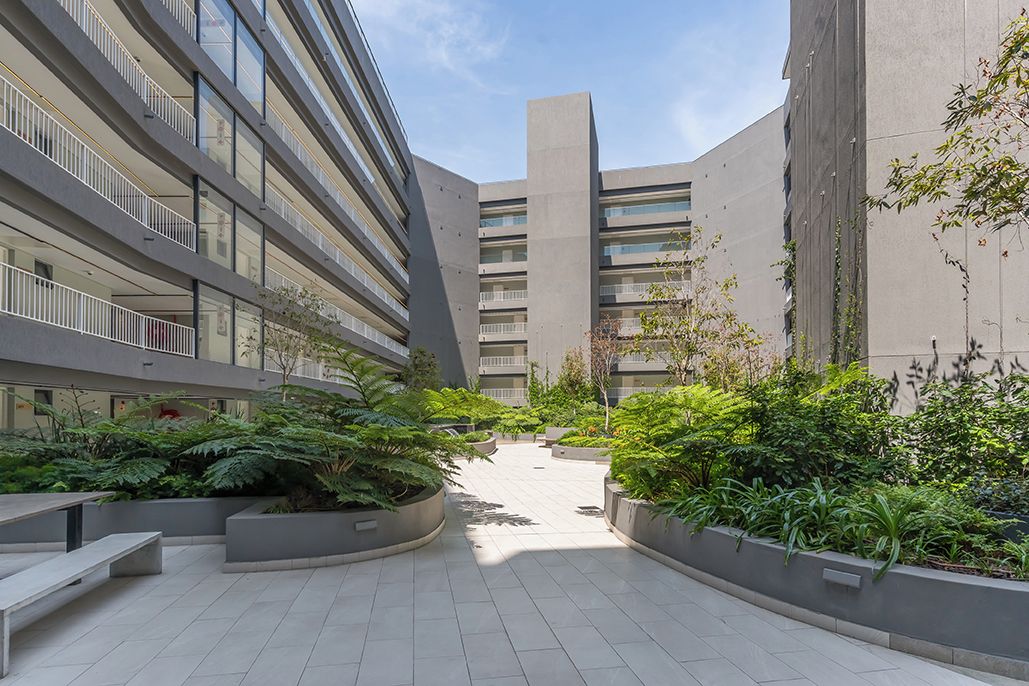 Un bâtiment moderne doté de nombreux balcons et d’une cour intérieure agrémentée de jardinières.