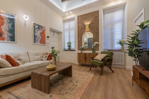 Een woonkamer met een bank, fauteuil, salontafel en een open haard.