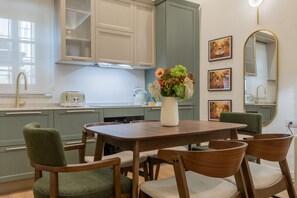 A modern kitchen with a dining area, featuring a wooden table and chairs, a vase of flowers, and artwork on the walls. - San Francesco Boutique House by Wonderful Italy (Turin)