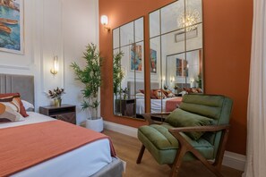 A hotel room with a large bed, a green armchair, a mirror, and a potted plant. - San Francesco Boutique House by Wonderful Italy (Turin)