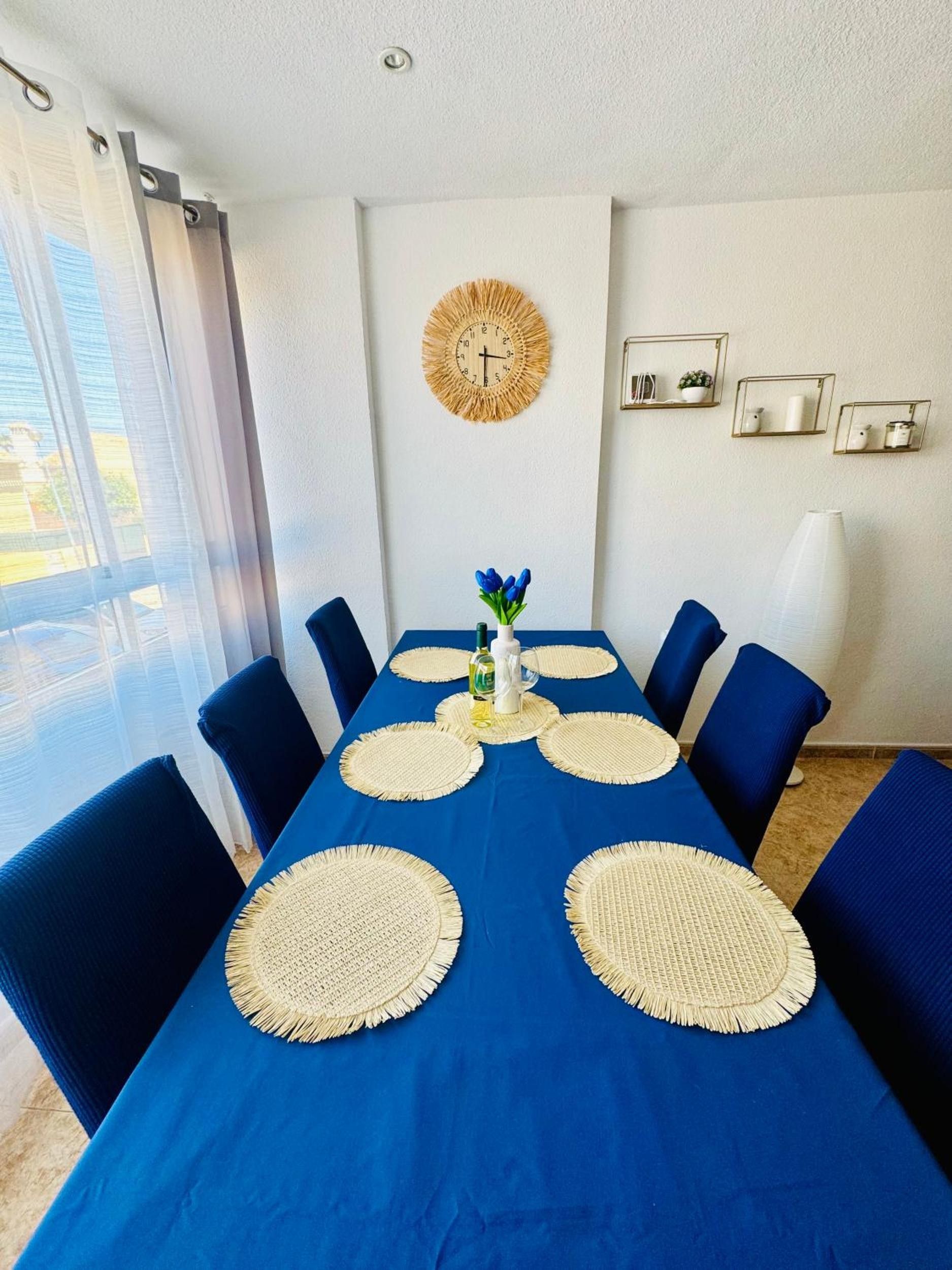 Un comedor con mantel azul, individuales tejidos y sillas azules.