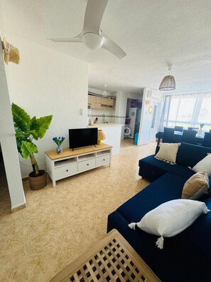 A modern living room with a TV, sofa, and a ceiling fan. - Apartment 'La Manguita' with Shared Pool, Wi-Fi and Air Conditioning (Playa Honda)