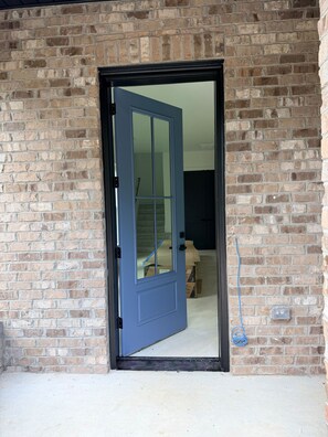 A blue door with a glass panel, leading into a room with a visible bed and a wall-mounted electrical box. - NEW! Walk Neyland Vintage Vol Theme - 3 master bedroom, rooftop deck w/ Hottub. (Knoxville)