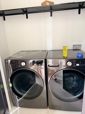 Two front-loading LG ThinQ washing machines side by side in a laundry room. - NEW! Walk Neyland Vintage Vol Theme - 3 master bedroom, rooftop deck w/ Hottub. (Knoxville)