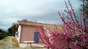 A single-story building with a tiled roof, a blue door, and a table outside.