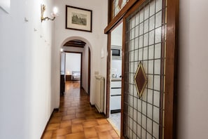 A hallway with a tiled floor, a radiator, and a door with a diamond-shaped glass panel. - Borgo Tegolaio House by MMega Homes and Villas (Florence)