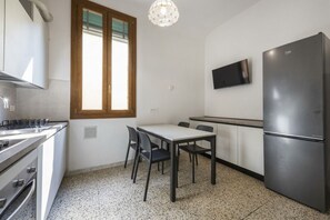 A compact kitchen with a dining table, chairs, a refrigerator, and a television mounted on the wall. - Borgo Tegolaio House by MMega Homes and Villas (Florence)