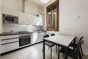Eine moderne Küche mit Mikrowelle, Herd, Backofen und einem Essbereich mit Tisch und Stühlen.