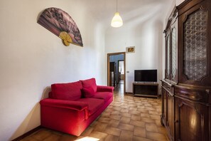 Ein Wohnzimmer mit einem roten Sofa, einem Fernseher und einem Holzschrank.