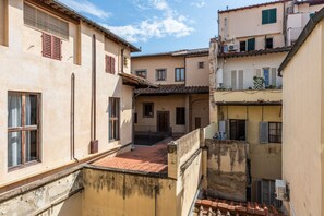 A narrow alleyway between buildings with a red-tiled roof, a small courtyard, and a staircase leading to an upper level. - Borgo Tegolaio House by MMega Homes and Villas (Florence)