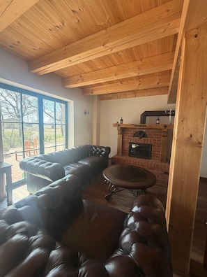 Ein gemütlicher Raum mit Ledersofa, rundem Tisch und Kamin aus Ziegelsteinen.