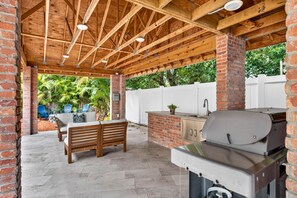 An outdoor patio with a brick barbecue grill, a sink, and a seating area with a table and chairs. - 4BR Historic Ybor Home | Sleeps 9 | 3.5 Baths (Tampa)