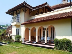 A two-story building with a balcony and a covered patio area with seating. - Cozzy Villa Bintang Batulayang (bOGOR)