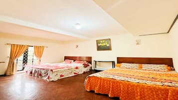 A hotel room with two beds, a wooden floor, and a window with curtains.