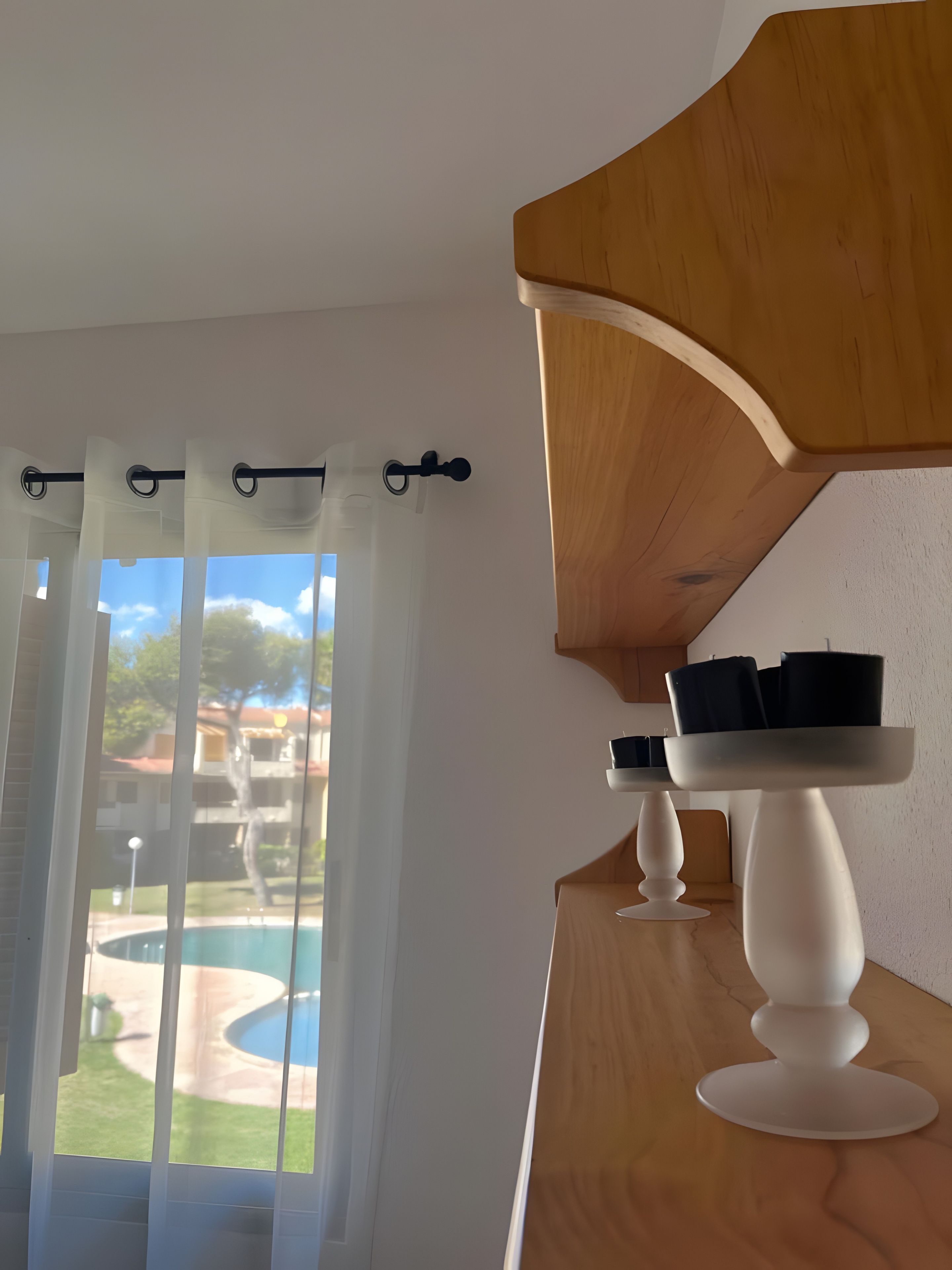 Ein Zimmer mit Blick auf einen Swimmingpool, einer Holzbalkendecke und einem weißen Tisch mit schwarzen Gegenständen.