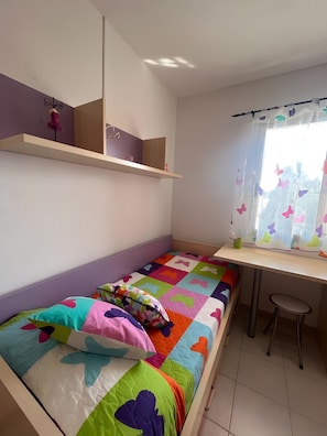 A bedroom with a bed, a desk, and a chair.