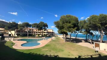 Een resort met een zwembad, bomen en uitzicht op zee.
