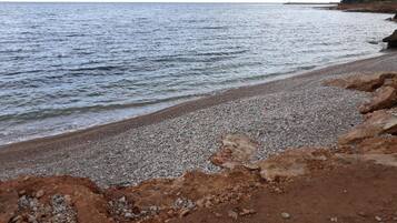 A pebbled beach with a rocky shoreline and calm sea.