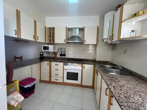 Cozinha com armários brancos, micro-ondas, fogão e pia.