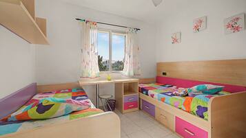 Un dormitorio infantil con dos camas, un escritorio y una ventana con cortinas.
